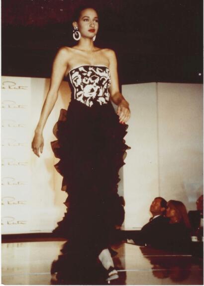 Model walking runway in strapless black-and-white patterned gown with ruffled black skirt.