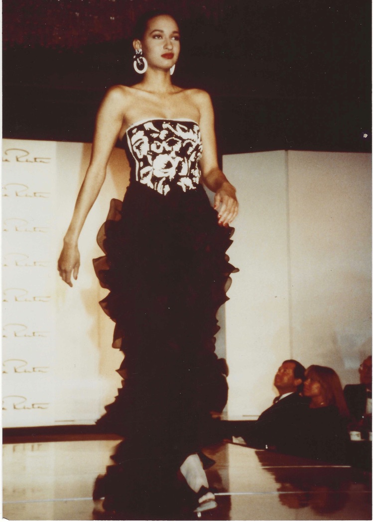 Model walking runway in strapless black-and-white patterned gown with ruffled black skirt.