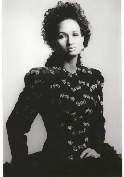 Black-and-white portrait of a woman in a patterned blouse, exuding elegance and confidence.