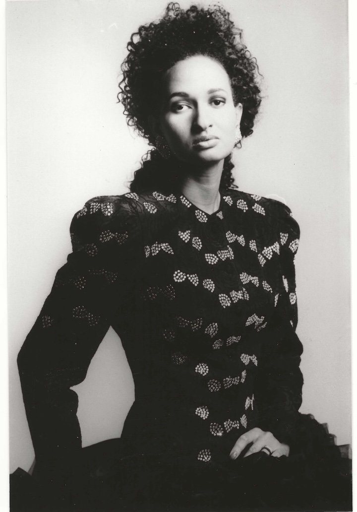 Black-and-white portrait of a woman in a patterned blouse, exuding elegance and confidence.
