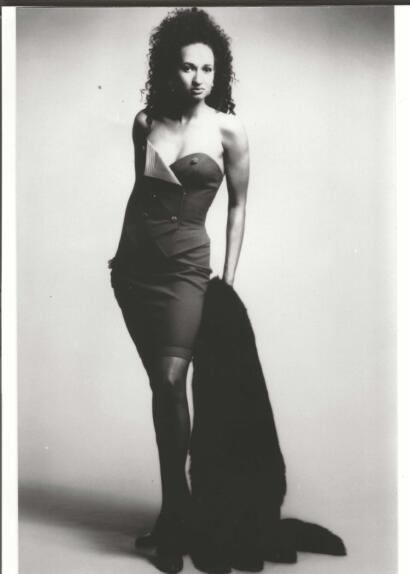 Black-and-white portrait of a woman in a strapless dress, holding a fur stole.