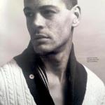 Black-and-white fashion portrait of a young male model wearing a cable-knit sweater and varsity jacket.