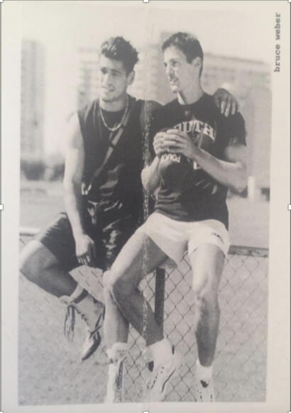 Two young men in athletic attire pose together outdoors, one holding a basketball.