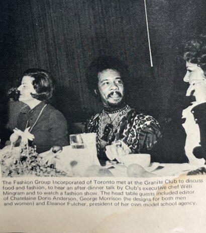 Black-and-white photo of three people at a table during a fashion event in Toronto.