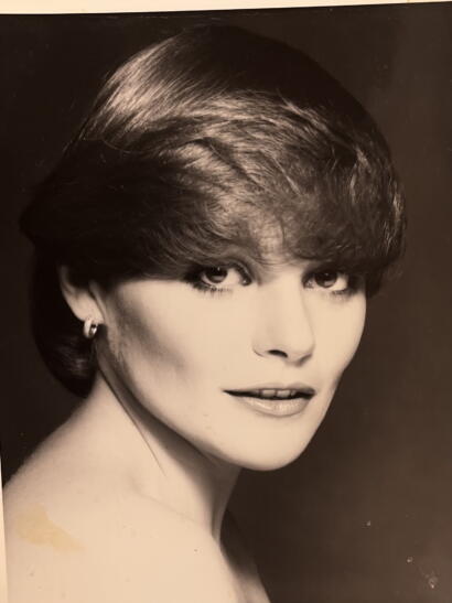 Black and white portrait of a woman with short, wavy hair, wearing hoop earrings.