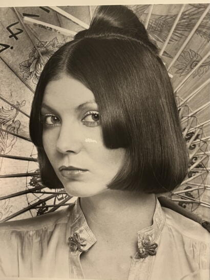 Black and white portrait of a woman with sleek, straight bob hairstyle, wearing a traditional embroidered garment.