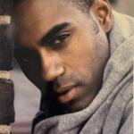 Close-up of a young man's face, showcasing his stylish haircut and casual grey hoodie.