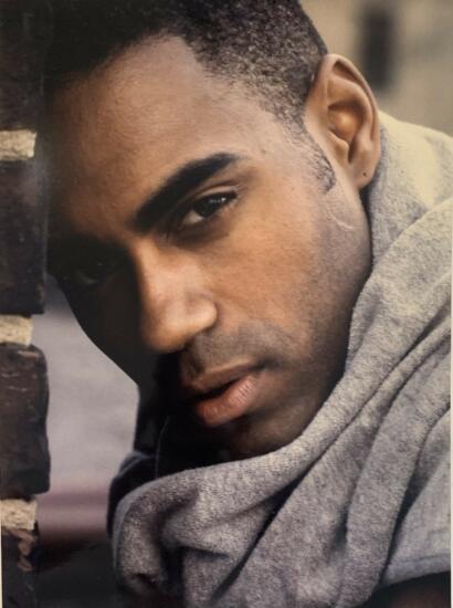 Close-up of a young man's face, showcasing his stylish haircut and casual grey hoodie.
