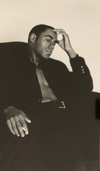 Black and white portrait of a young man with short hair, wearing a partially open jacket, sitting thoughtfully.