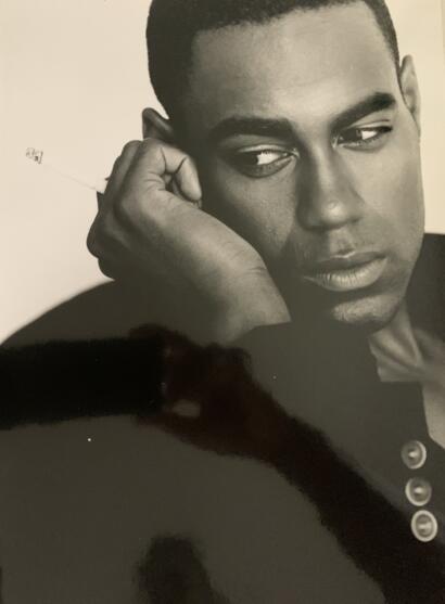 Black and white portrait of a young man with contemplative expression, resting his face on his hand.