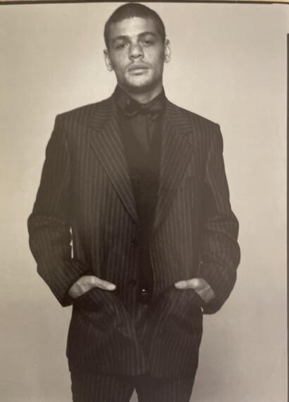 Man in a pinstripe suit with hands in pockets, wearing a bow tie, photo in black and white.