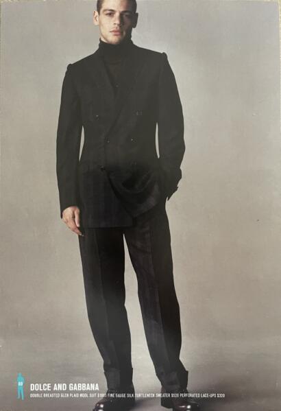 Male model in a tailored black double-breasted wool suit, paired with a sheer turtleneck, for a high-fashion look.