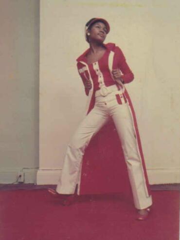 Woman in vintage red and white stylish outfit with high-waisted pants, coat, and beret.