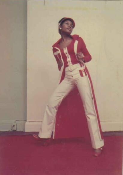 Woman in vintage red and white stylish outfit with high-waisted pants, coat, and beret.