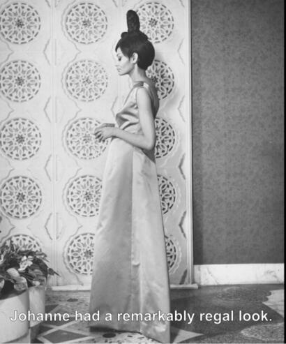 Black-and-white image of a woman in elegant evening wear, standing sideways against a decorative wall.