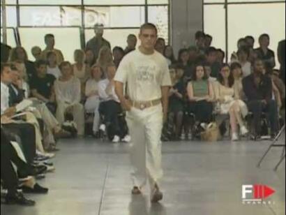 Model walking runway in a white matching ensemble during a fashion show.