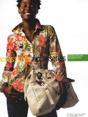 Model wearing a colorful floral patterned shirt, holding a woven beige handbag, for a fashion accessories advertisement.
