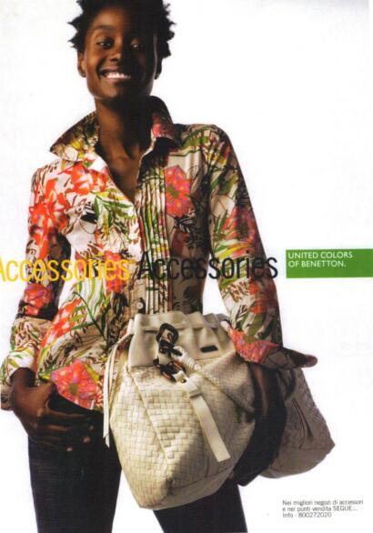 Model wearing a colorful floral patterned shirt, holding a woven beige handbag, for a fashion accessories advertisement.