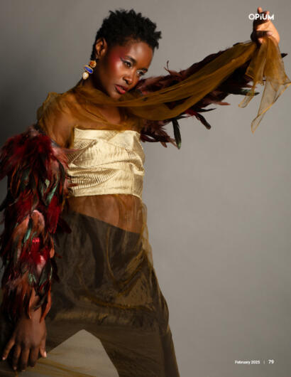Model in layered gold, sheer fabrics and feather details.
