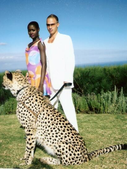 Models pose outdoors with a cheetah, showcasing vibrant summer fashion against lush greenery.