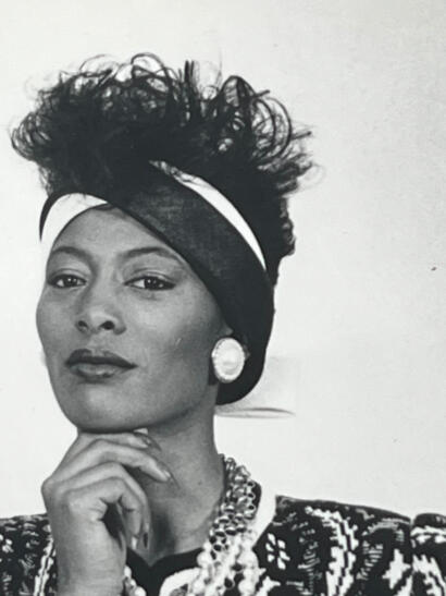 Elegant portrait of a woman wearing vintage accessories, featuring a headscarf, large earrings, and layered necklaces.