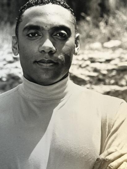 Portrait of a woman with braided hair wearing a turtleneck, outdoors in black and white.