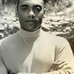 Male model in a turtleneck, with crossed arms, outdoors in black and white.