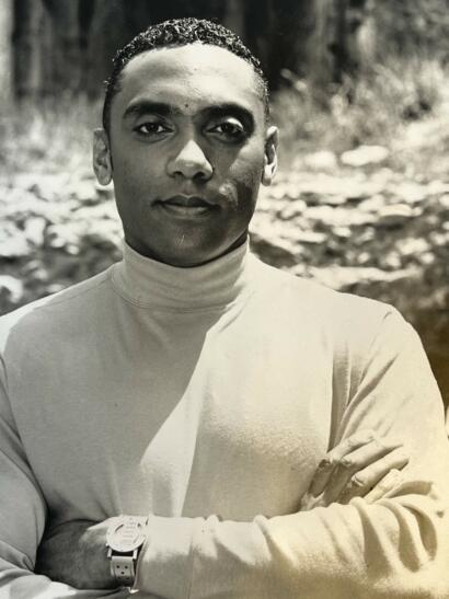 Male model in a turtleneck, with crossed arms, outdoors in black and white.