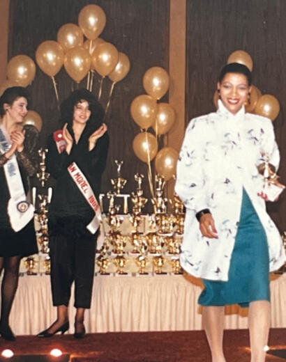 Women on stage with trophies and gold balloons at an award ceremony.