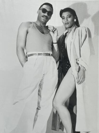 Stylish duo poses confidently, showcasing vintage fashion in black and white.