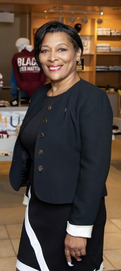 Elegant woman in a dark blazer and black-and-white skirt at an indoor event.