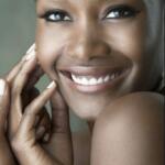 Close-up of a smiling woman with smooth skin, bright eyes, and natural makeup.