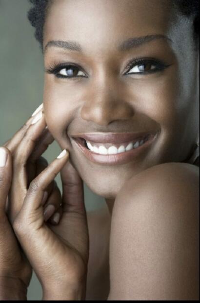 Close-up of a smiling woman with smooth skin, bright eyes, and natural makeup.
