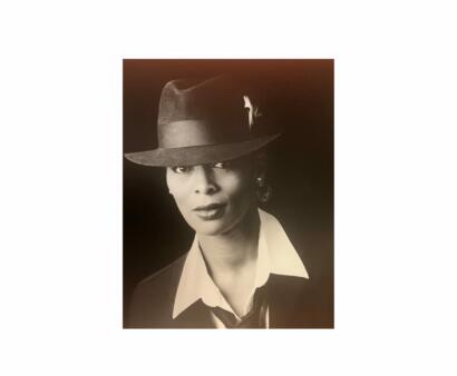 Black-and-white portrait of a woman wearing a stylish hat with a feather, dressed in formal attire.
