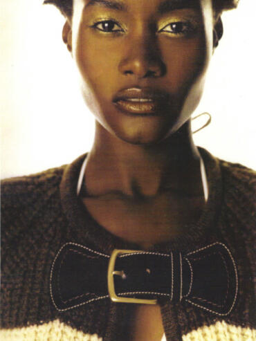 Close-up of a woman with gold eyeshadow and a textured jacket featuring a bow detail.