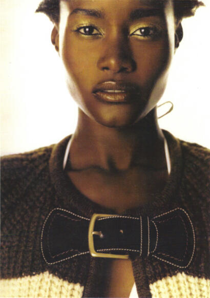 Close-up of a woman with gold eyeshadow and a textured jacket featuring a bow detail.