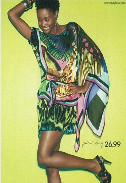 Woman in colorful patterned top and shorts, accessorized with jewelry, against a bright yellow background.