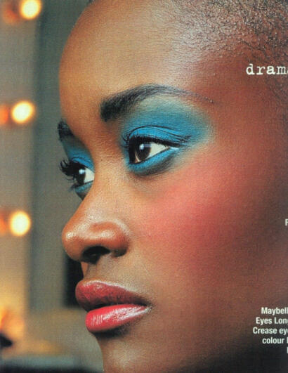 Close-up of a woman's face showcasing bold blue eyeshadow and flawless makeup.