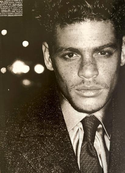 Black-and-white portrait of a young man with a serious expression, wearing a suit and tie.