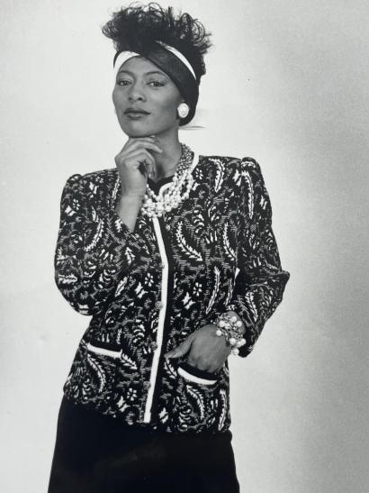 Elegant woman in vintage 80s fashion with styled hair, jewelry, and patterned blazer.