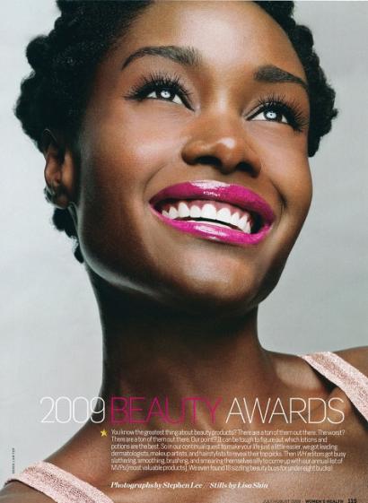 Close-up of a smiling woman with radiant skin and bold pink lipstick.