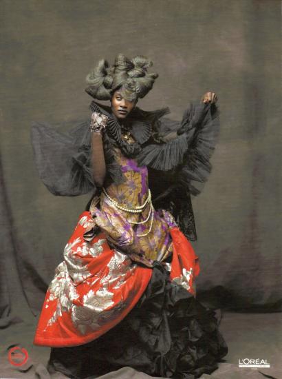 Fashion model in elaborate kimono-inspired garment with dramatic black ruffles and styled hair.