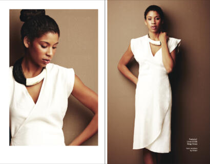 Elegant woman in a white linen and silk wrap dress, accessorized with a horn necklace.