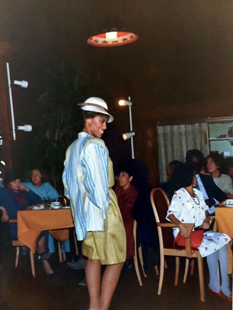 Fashionable woman in vintage-inspired outfit posing in a cozy indoor restaurant setting.